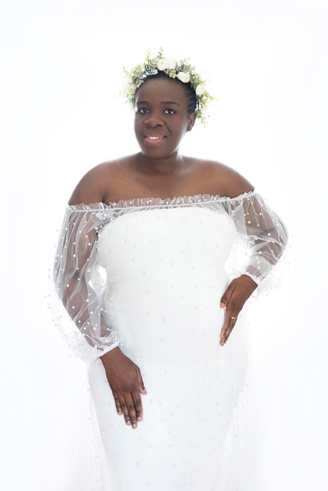 Captivating indoor maternity portrait in Essex with a minimalist white gown and soft lighting