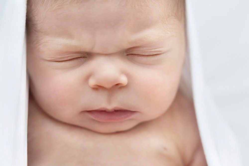 Close-up of newborn baby’s scrunched face, capturing precious expression in Essex photoshoot