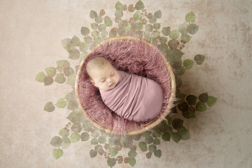 Sleeping newborn girl in pink fur basket with eucalyptus leaves, sweet Essex portrait