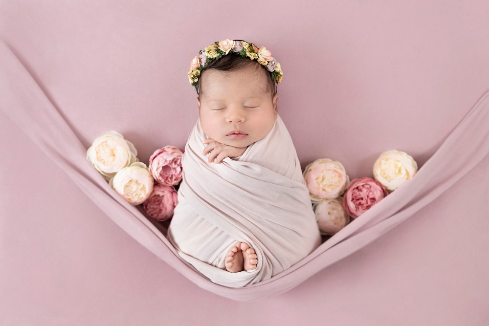 Newborn girl swaddled in pink with floral crown and peonies, delicate Essex baby photography