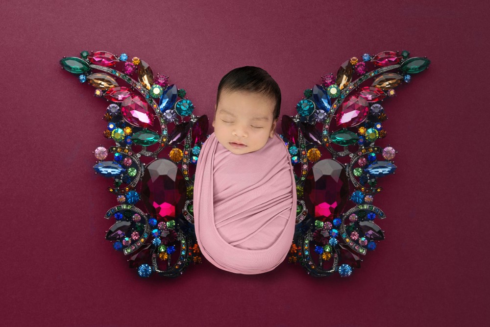 Swaddled newborn girl with gem-studded butterfly wings, colourful Essex baby portrait