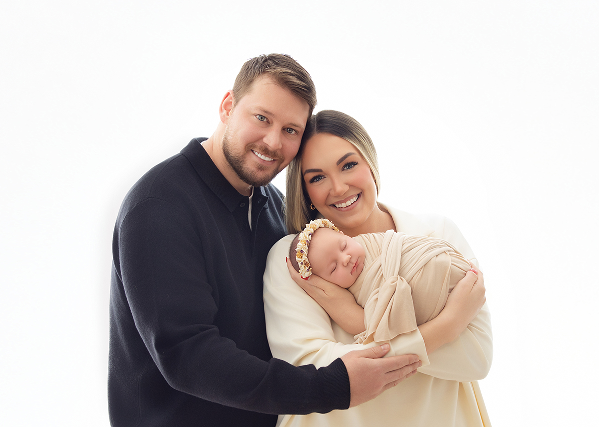 Happy parents holding their sleeping newborn baby during a natural family portrait photographed by a professional newborn photographer in Braintree Essex.