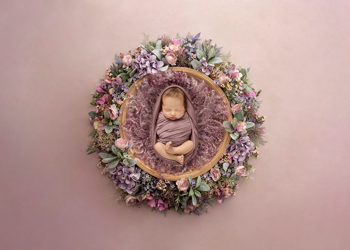 Artistic newborn baby portrait surrounded by pastel floral wreath and soft textures photographed during creative newborn photography session in Maldon Essex.