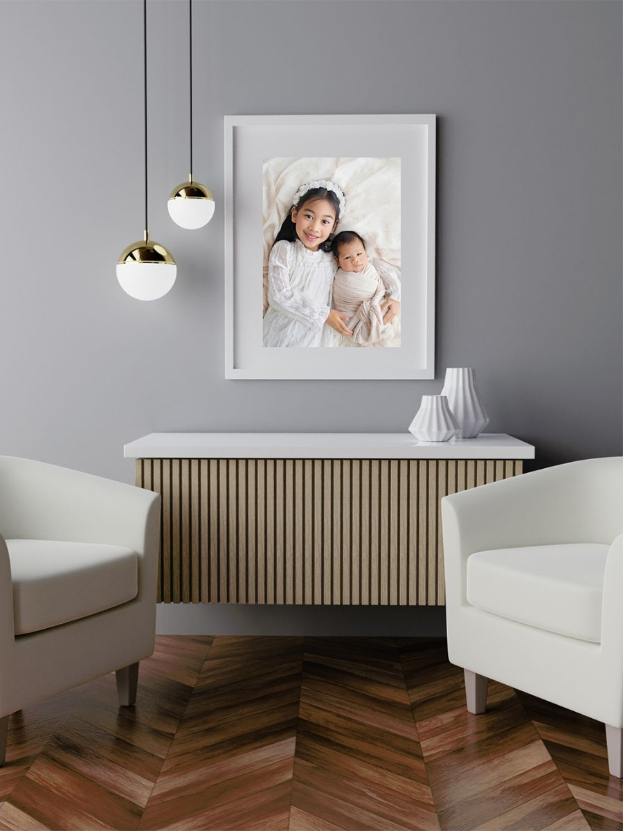 Framed newborn and sibling portrait displayed as fine art wall artwork in a modern Brentwood Essex home interior with soft neutral styling