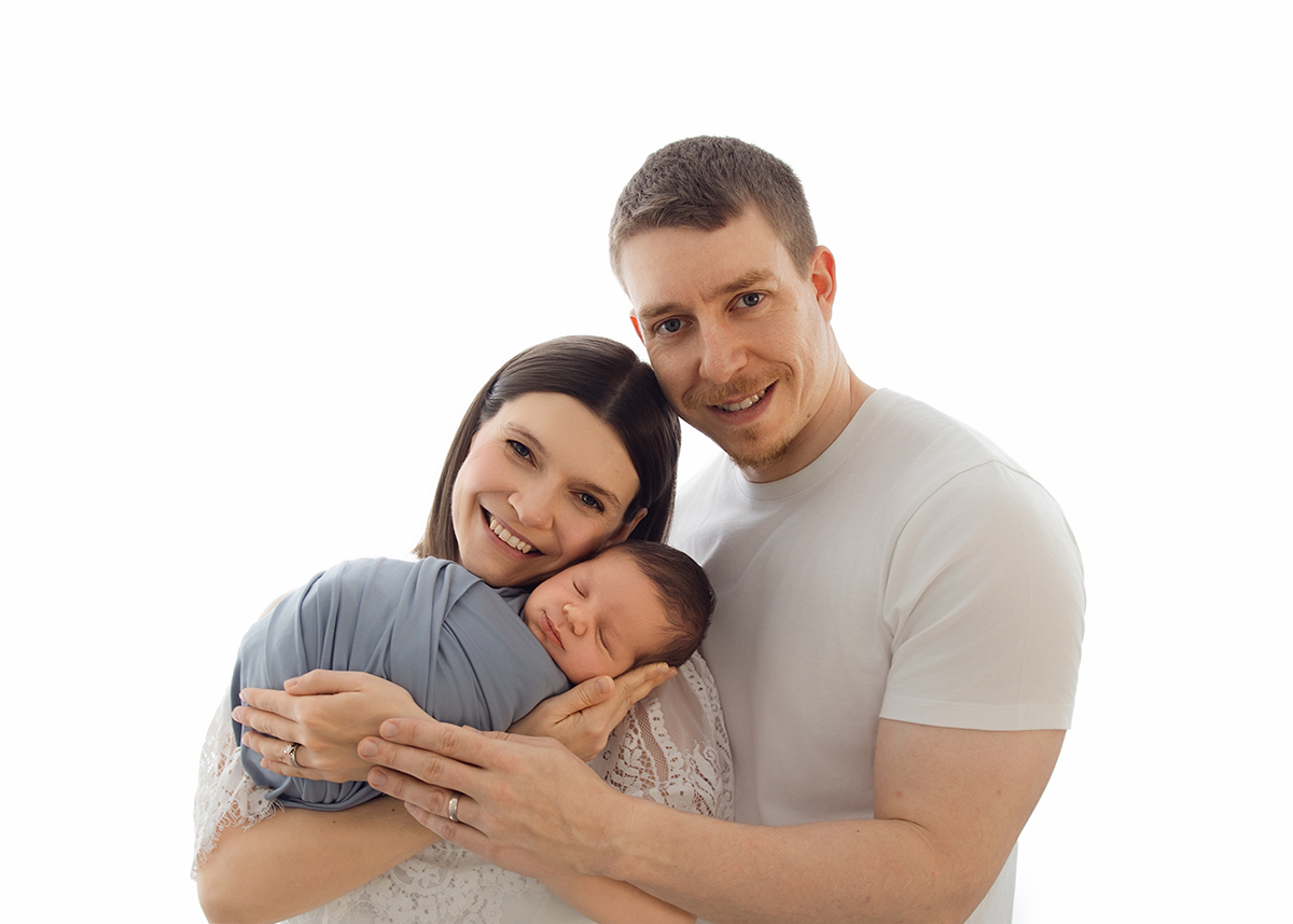 Parents holding their sleeping newborn baby during an in-home newborn photography session in Essex.